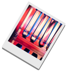 Vier senkrecht stehende Reagenzgläser mit farbigen Flüssigkeiten in einem Halter, Hintergrund in Rot- und Blautönen.