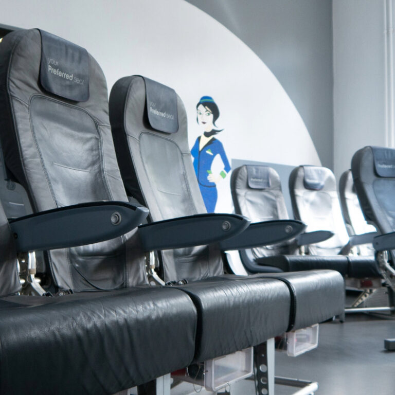 Schwarze Ledersitze mit Kopfstützen, auf denen 'Your Preferred Seat' steht, in zwei Reihen vor einer Wand